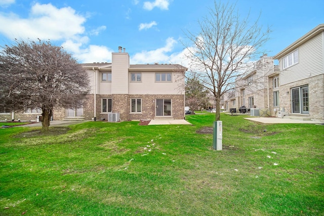 back of house featuring cooling unit, a patio area, and a lawn