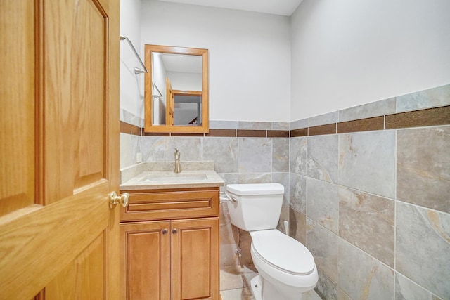 bathroom with tile walls, vanity, and toilet