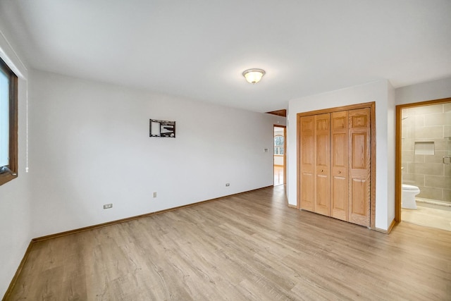 unfurnished bedroom with connected bathroom, a closet, and light wood-type flooring