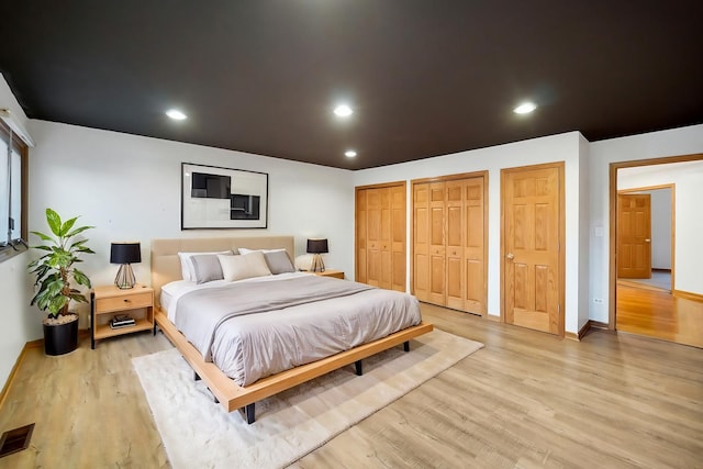 bedroom with multiple closets and light wood-type flooring