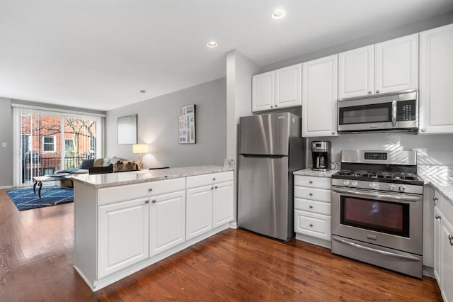 kitchen featuring kitchen peninsula, stainless steel appliances, white cabinets, and dark hardwood / wood-style floors