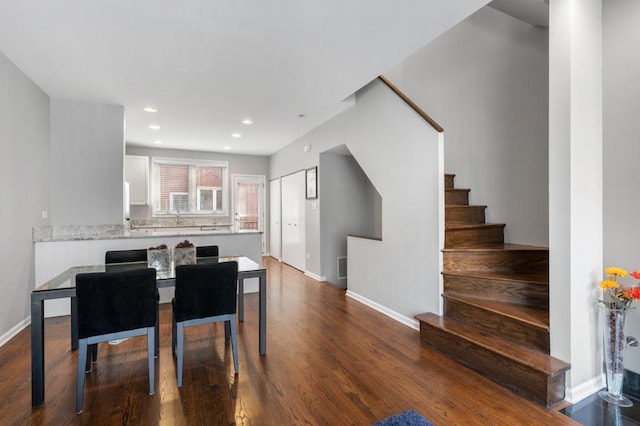 kitchen with white cabinetry, light stone counters, wood-type flooring, and sink