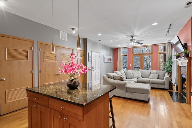 kitchen featuring ceiling fan, decorative light fixtures, track lighting, a kitchen island, and light hardwood / wood-style flooring