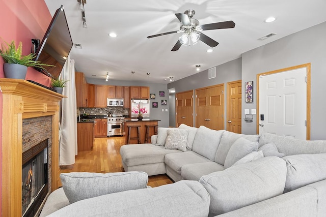 living room featuring ceiling fan, light hardwood / wood-style floors, and a fireplace