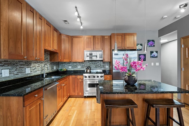 kitchen featuring stainless steel appliances, sink, a kitchen breakfast bar, dark stone countertops, and a center island