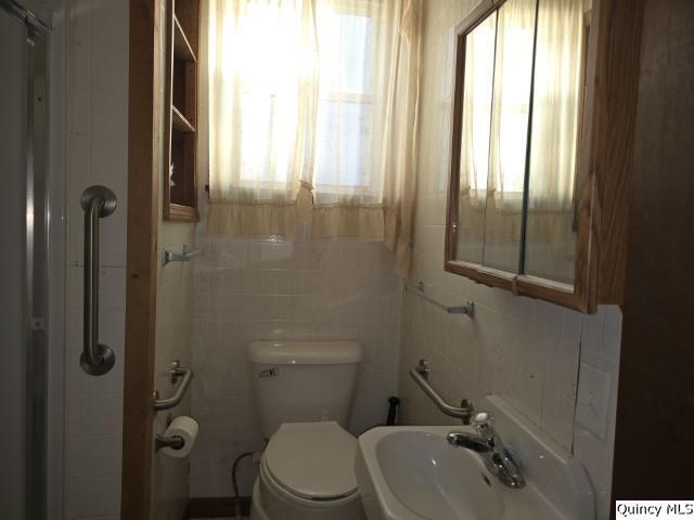 bathroom featuring tile walls, sink, and toilet