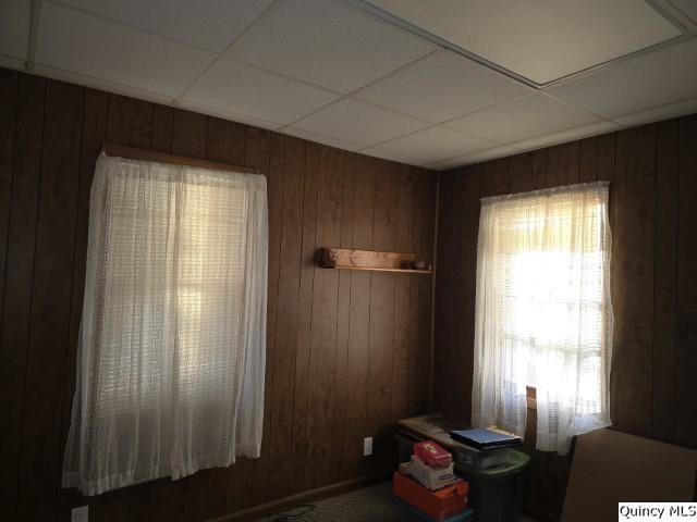 interior space with a paneled ceiling and wood walls