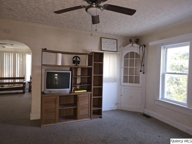 unfurnished living room with ceiling fan, plenty of natural light, a textured ceiling, and carpet flooring