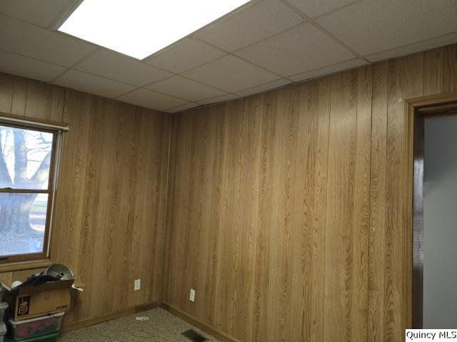 empty room with a paneled ceiling and wood walls