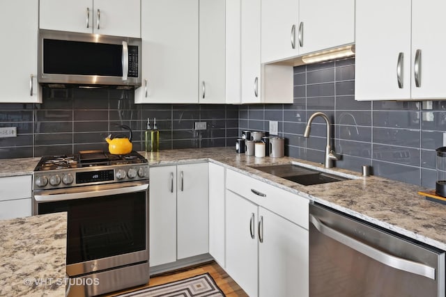 kitchen with appliances with stainless steel finishes, white cabinets, and a sink