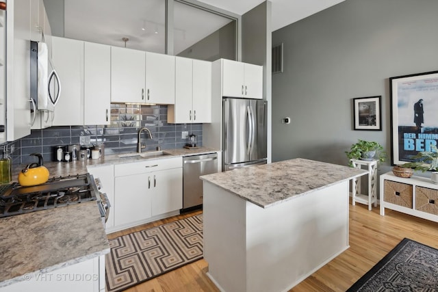 kitchen with visible vents, a sink, stainless steel appliances, light wood-type flooring, and backsplash