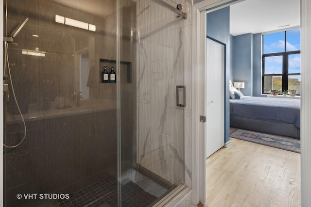 ensuite bathroom featuring a shower stall, connected bathroom, and wood finished floors