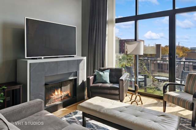 living area with a wall of windows, wood finished floors, and a tile fireplace