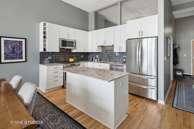 kitchen with white cabinetry, light wood-style flooring, appliances with stainless steel finishes, and backsplash