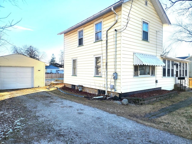 view of home's exterior featuring driveway, a detached garage, and an outdoor structure