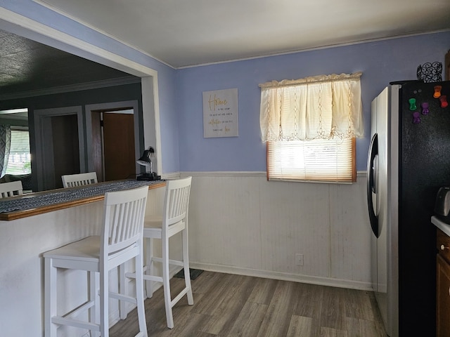 kitchen with ornamental molding, freestanding refrigerator, a wainscoted wall, and wood finished floors