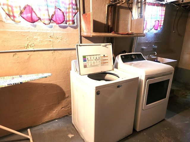 laundry area with concrete block wall, laundry area, and washer and clothes dryer