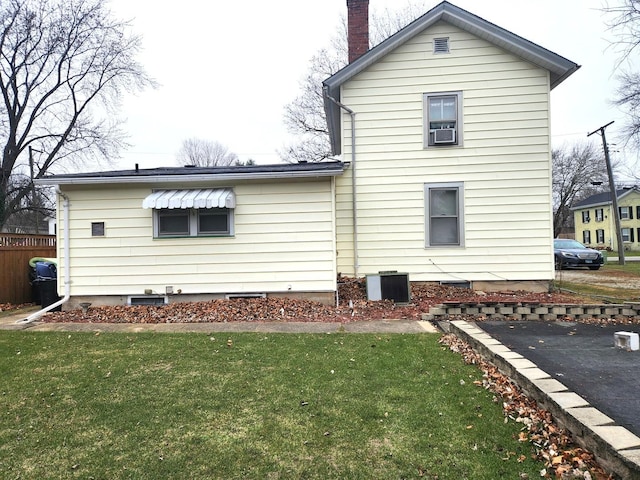 back of house featuring a chimney, cooling unit, fence, and a lawn