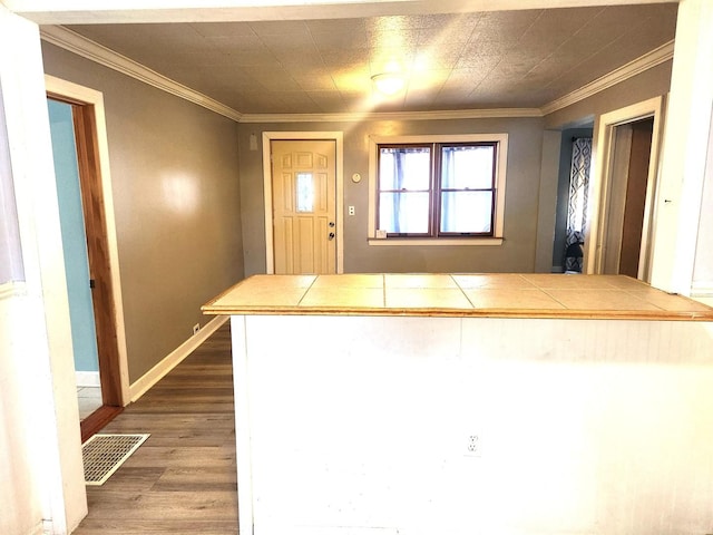 interior space featuring ornamental molding, wood finished floors, visible vents, and baseboards