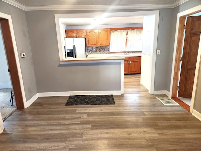 kitchen featuring fridge with ice dispenser, visible vents, light countertops, and wood finished floors