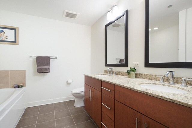 bathroom featuring a tub to relax in, toilet, vanity, and tile patterned flooring