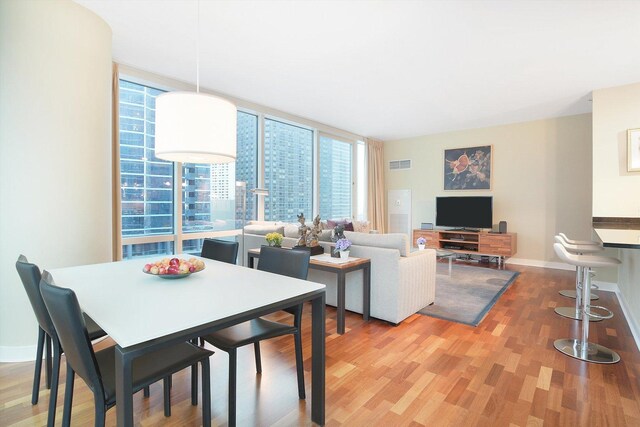 dining area with expansive windows and hardwood / wood-style floors