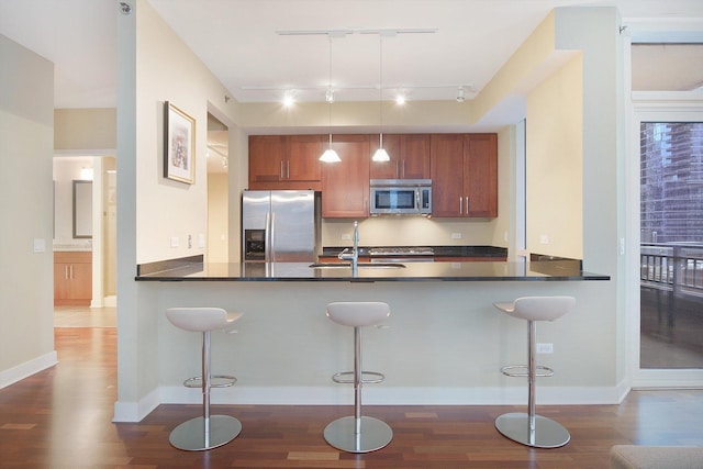 kitchen with stainless steel appliances, hanging light fixtures, kitchen peninsula, and a kitchen bar