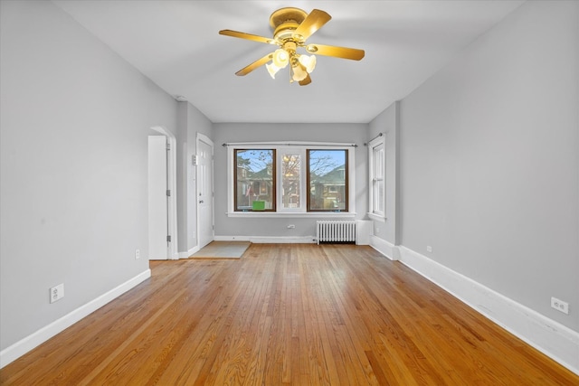 unfurnished living room featuring ceiling fan, light hardwood / wood-style floors, and radiator