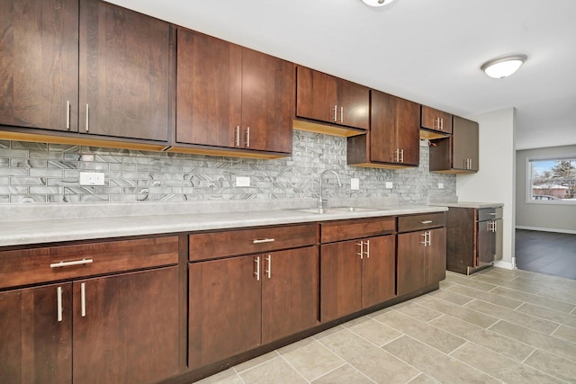 kitchen featuring decorative backsplash, sink, light tile patterned floors, and dark brown cabinets