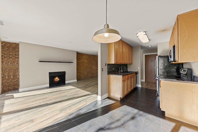 kitchen with brick wall, decorative light fixtures, sink, backsplash, and dark tile patterned floors