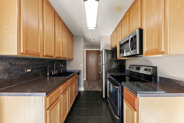 kitchen with tasteful backsplash, appliances with stainless steel finishes, sink, and dark tile patterned floors