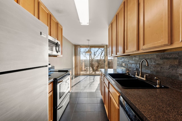 kitchen featuring appliances with stainless steel finishes, tasteful backsplash, sink, dark tile patterned flooring, and hanging light fixtures