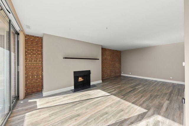 unfurnished living room featuring brick wall and wood-type flooring