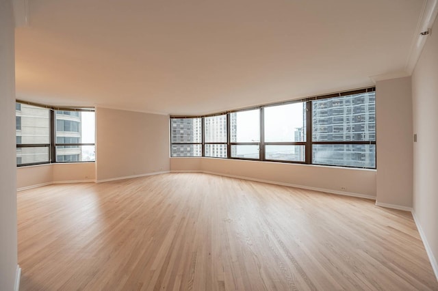 unfurnished room with crown molding, a healthy amount of sunlight, and light wood-type flooring