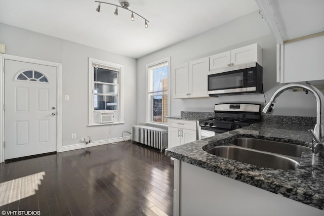 kitchen featuring radiator, white cabinetry, sink, dark stone countertops, and appliances with stainless steel finishes