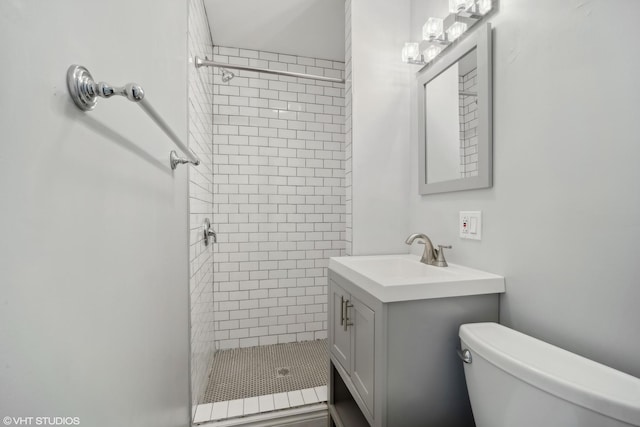 bathroom featuring vanity, toilet, and tiled shower