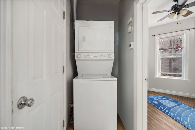 washroom with wood-type flooring, stacked washer / dryer, and ceiling fan