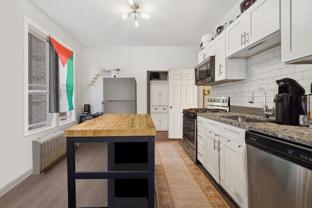 kitchen featuring white cabinetry, sink, appliances with stainless steel finishes, and dark stone counters