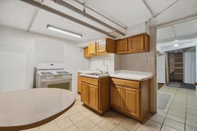 kitchen featuring white gas stove, light tile patterned flooring, and sink