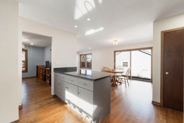 kitchen featuring dark stone countertops, white cabinetry, light hardwood / wood-style floors, and kitchen peninsula