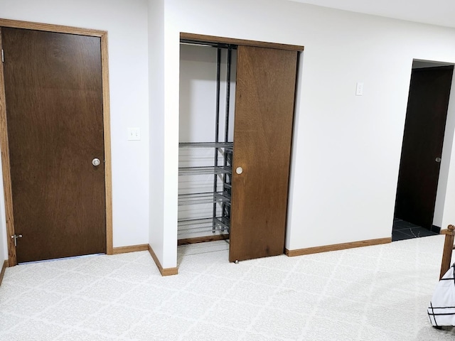 unfurnished bedroom with light colored carpet and a closet