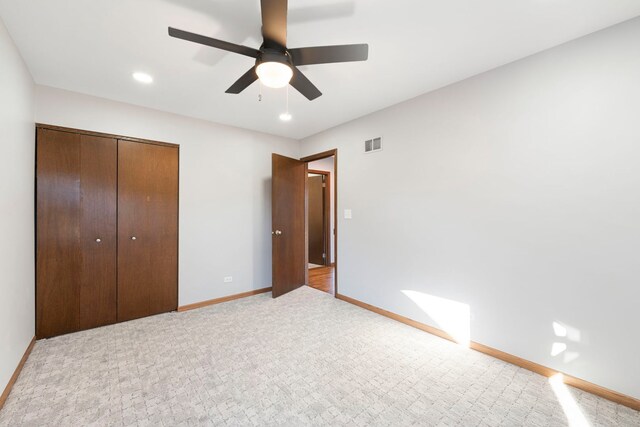 unfurnished bedroom featuring light carpet, ceiling fan, and a closet