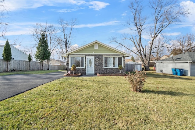 ranch-style house featuring a storage unit and a front lawn