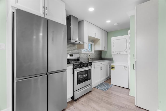 kitchen with white cabinetry, sink, wall chimney exhaust hood, stainless steel appliances, and stacked washer / dryer