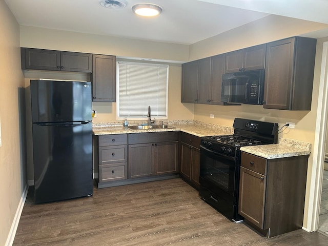 kitchen featuring black appliances, sink, light stone counters, dark brown cabinets, and dark hardwood / wood-style flooring