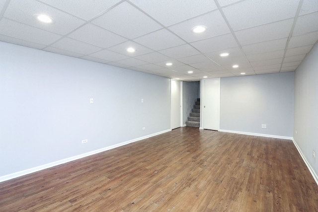 interior space with a drop ceiling and wood-type flooring