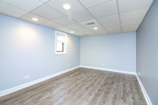 spare room with a paneled ceiling and light hardwood / wood-style flooring