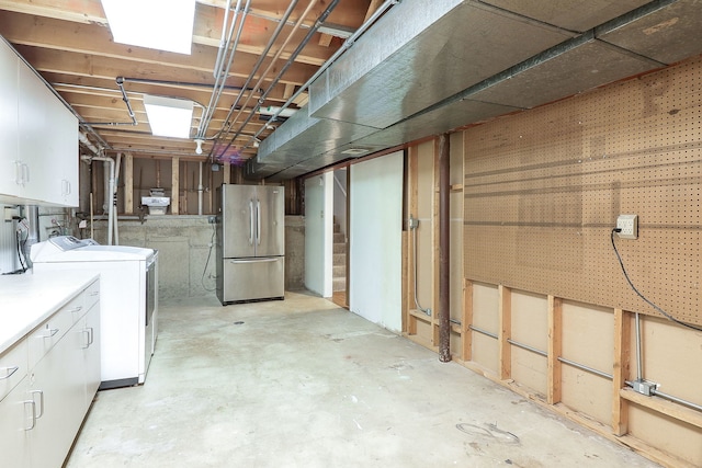 basement featuring stainless steel refrigerator and independent washer and dryer