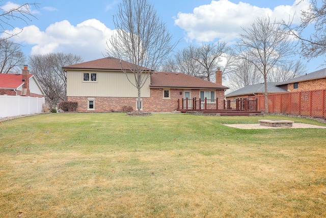 rear view of house with a wooden deck, a yard, and an outdoor fire pit