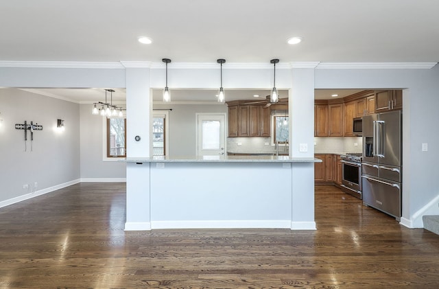 kitchen featuring high end appliances, hanging light fixtures, decorative backsplash, ornamental molding, and light stone counters